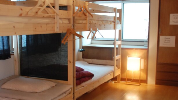 Une chambre avec deux lits superposés, un luminaire suspendu, une fenêtre et une lampe de chevet.