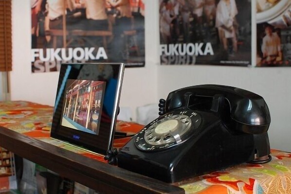 A vintage black rotary phone on a table with a colorful tablecloth.