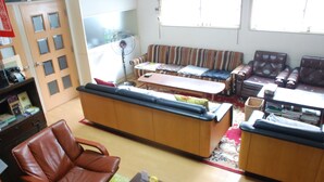 Un salon comprenant un canapé, un fauteuil, une table basse et un ventilateur.