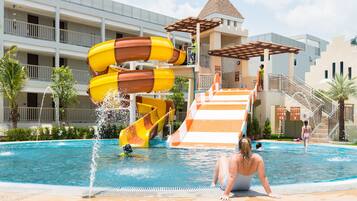 Un espace piscine d’hôtel doté de plusieurs toboggans et d’une terrasse à plusieurs niveaux.