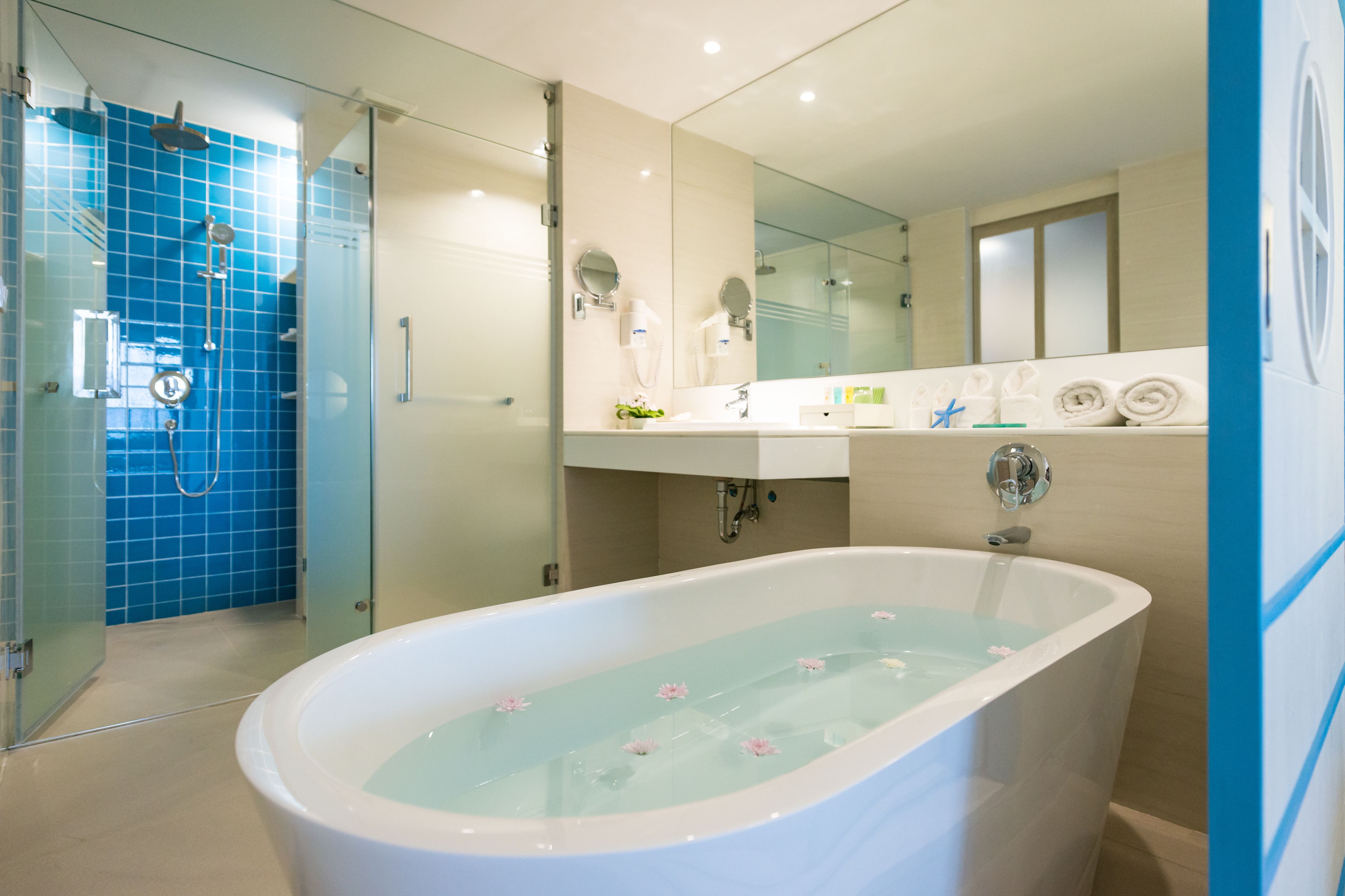 Une salle de bain moderne avec une douche à parois de verre, une baignoire sur pieds et un grand miroir au-dessus du lavabo.