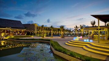 A well-lit outdoor area with a water feature, seating, and a pathway leading to a covered structure.