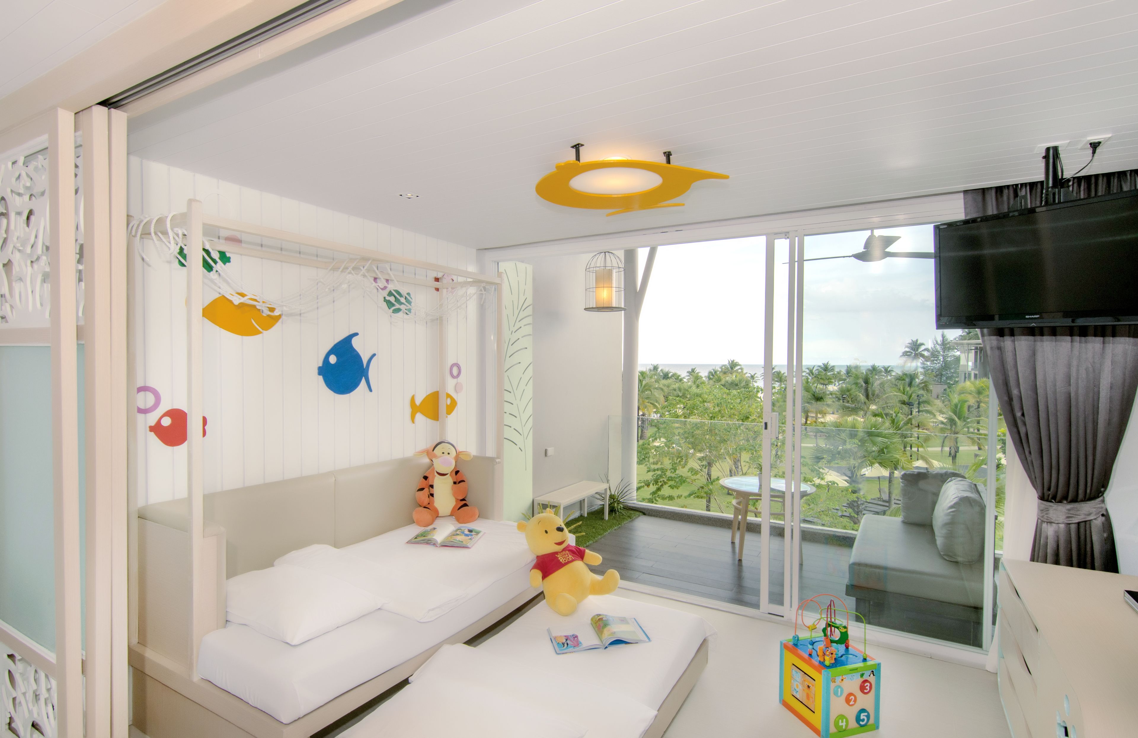 Ein Kinderzimmer mit Etagenbett, Spielzeug und einem großen Fenster mit Blick ins Grüne.