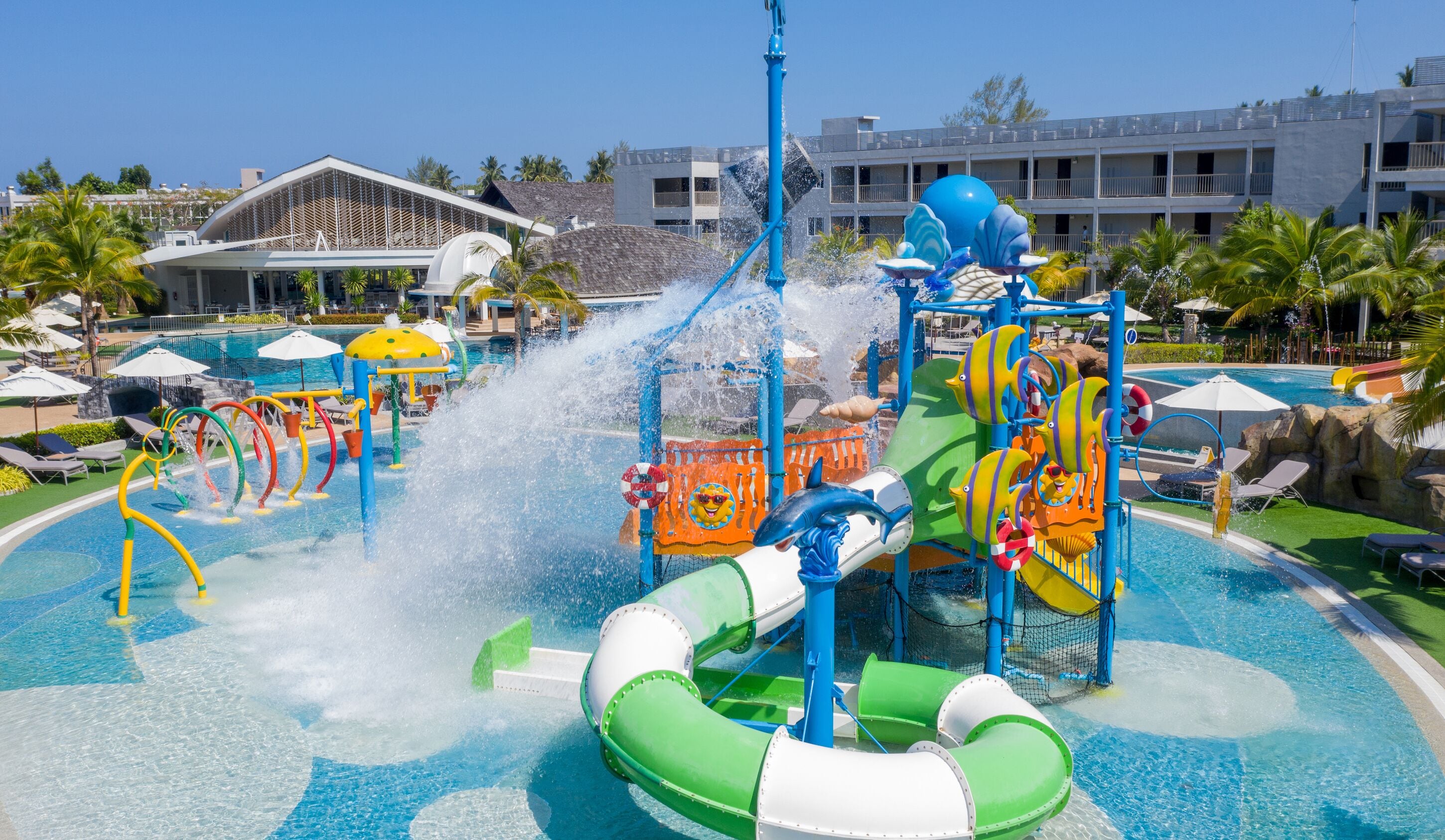 A water park with slides, a pool, and a building with balconies in the background.