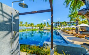 Una piscina con vistas a una zona de resort, incluyendo palmeras y sillas de descanso.