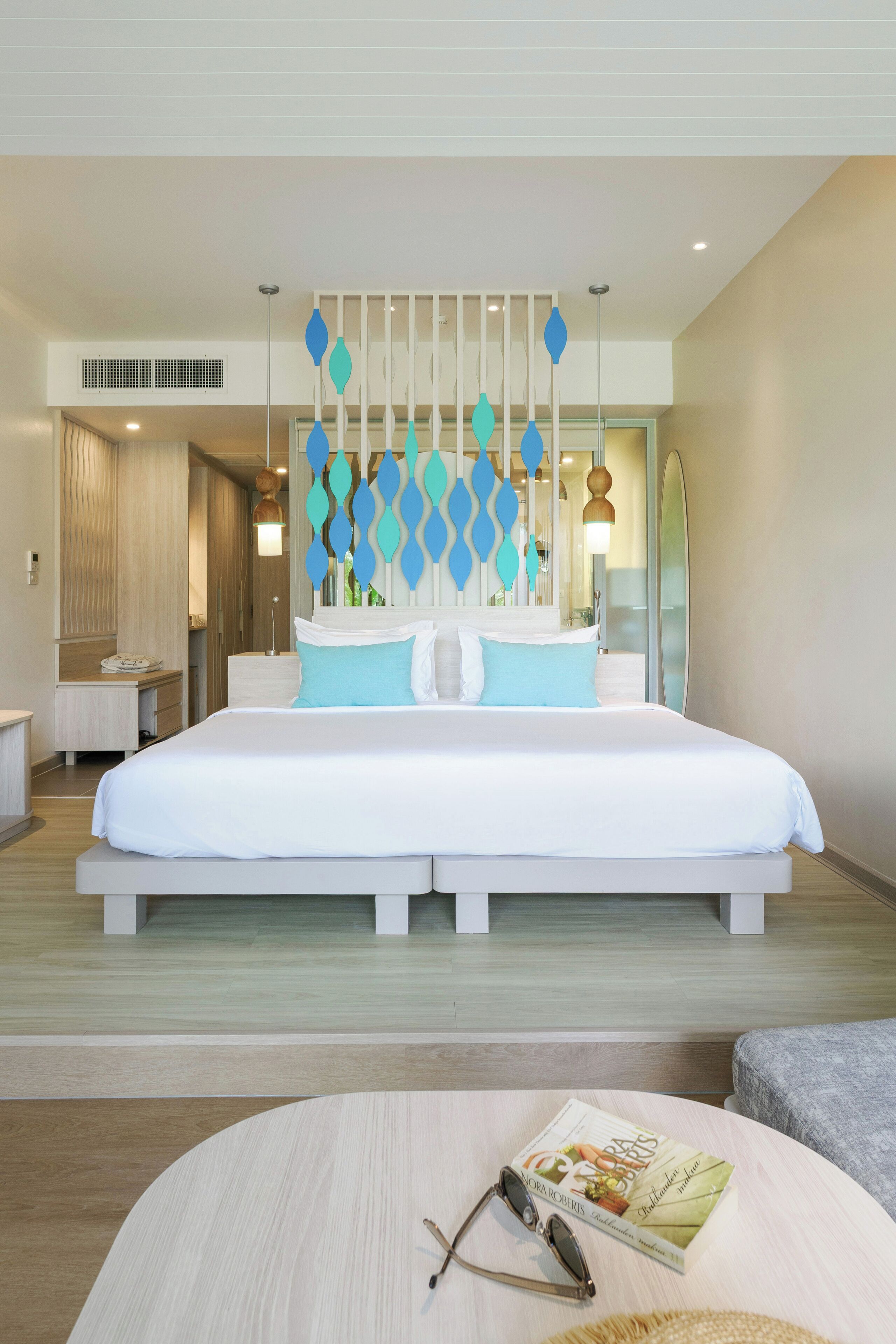 Een moderne hotelkamer met een groot bed, een nachtkastje, een ronde salontafel en een spiegel.