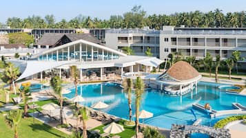 A resort with multiple swimming pools, a large covered area, and a view of palm trees.