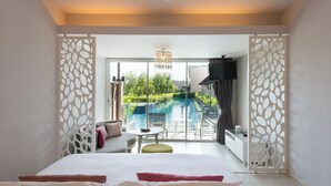 A hotel room with a bed, a sofa, a small table, and a view of an outdoor swimming pool. - The Sands Khao Lak by Katathani (Takua Pa)