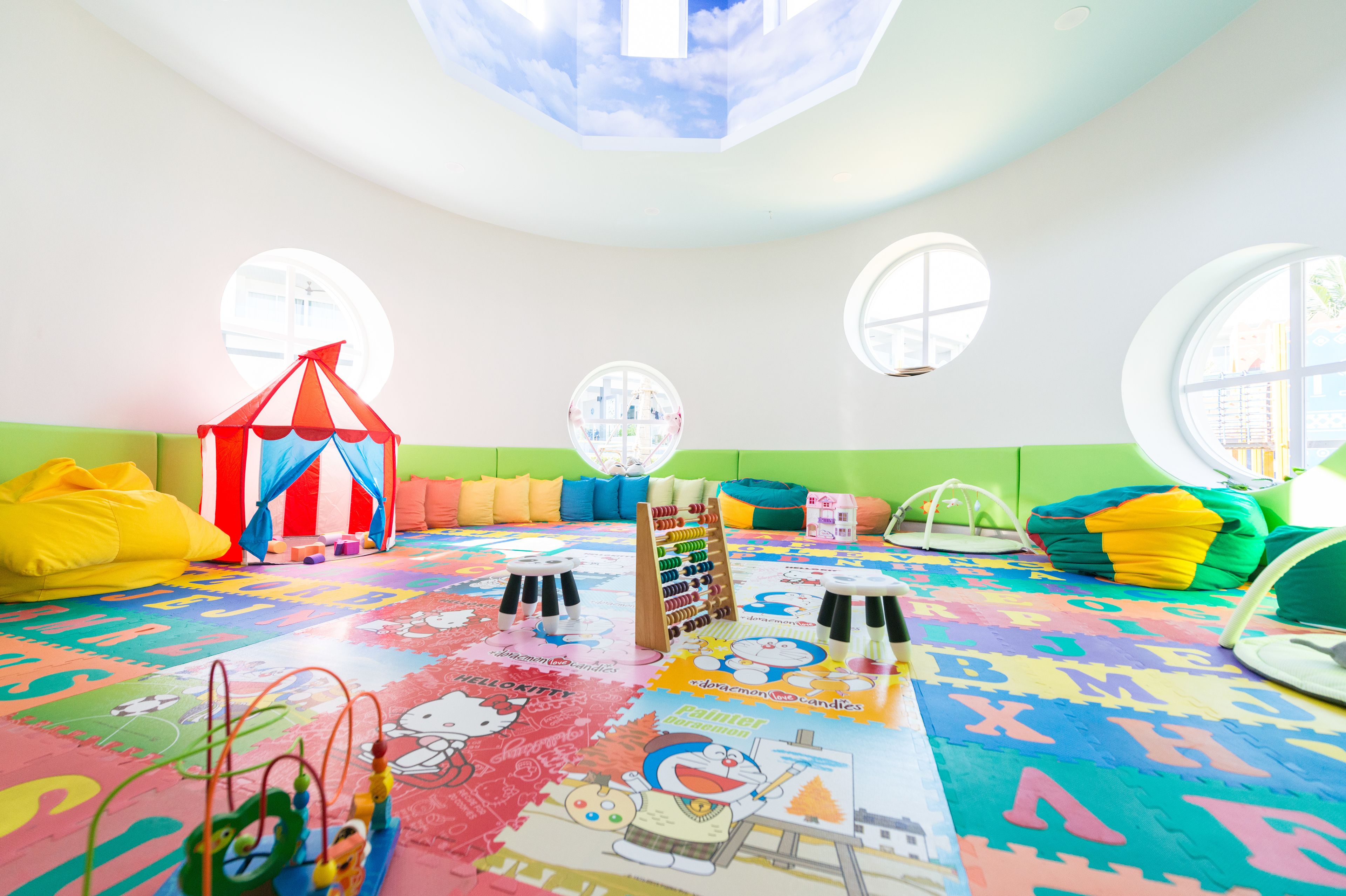 Een kinderspeelkamer met veel licht, een kleurrijke vloer, een klein circus tentje en een wereldbol.