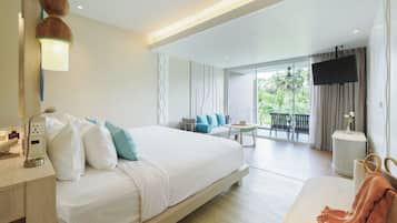A modern hotel room with a large bed, a desk with a lamp, a flat-screen TV, and a balcony with outdoor seating.