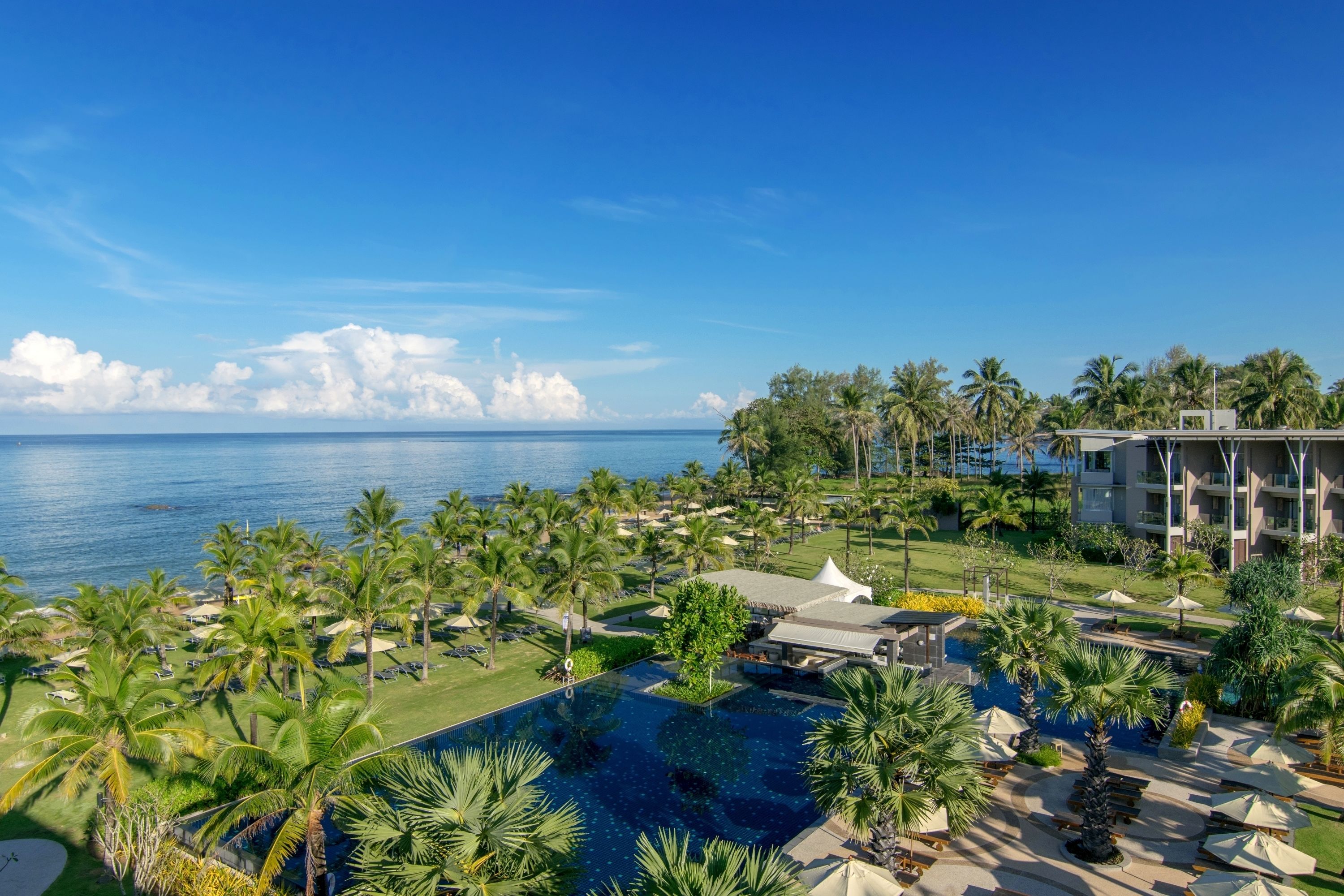 A resort with a large pool, palm trees, and a view of the ocean.
