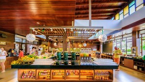 A buffet area with a variety of food items and beverages, wooden ceiling, and large windows. - The Sands Khao Lak by Katathani (Takua Pa)