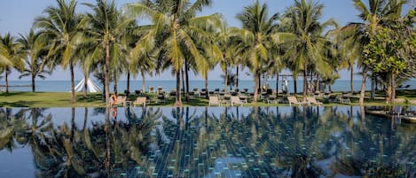 A pool with reflections of palm trees and a clear sky.