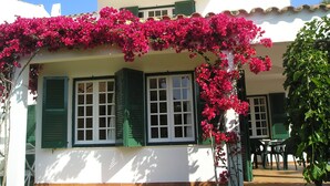 A white building with green shutters and a balcony covered in pink flowers. - Las Brisas I & II (Ciutadella de Menorca)