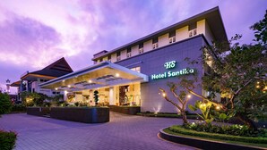 A modern hotel with a prominent entrance, a well-lit facade, and a landscaped garden area.