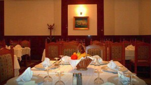 A dining area with tables set for a meal, a painting on the wall, and a chandelier. - El Biar Hotel (Algiers)