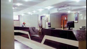 A reception area with a marble counter, a reception desk, and a computer monitor. - El Biar Hotel (Algiers)