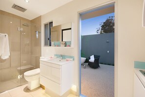 Un baño moderno con ducha envuelta en vidrio, un lavabo blanco y un espejo grande.