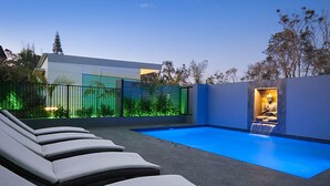A modern outdoor pool area with lounge chairs, a clear blue pool, and a statue in a niche. - Cavvanbah (Byron Bay)