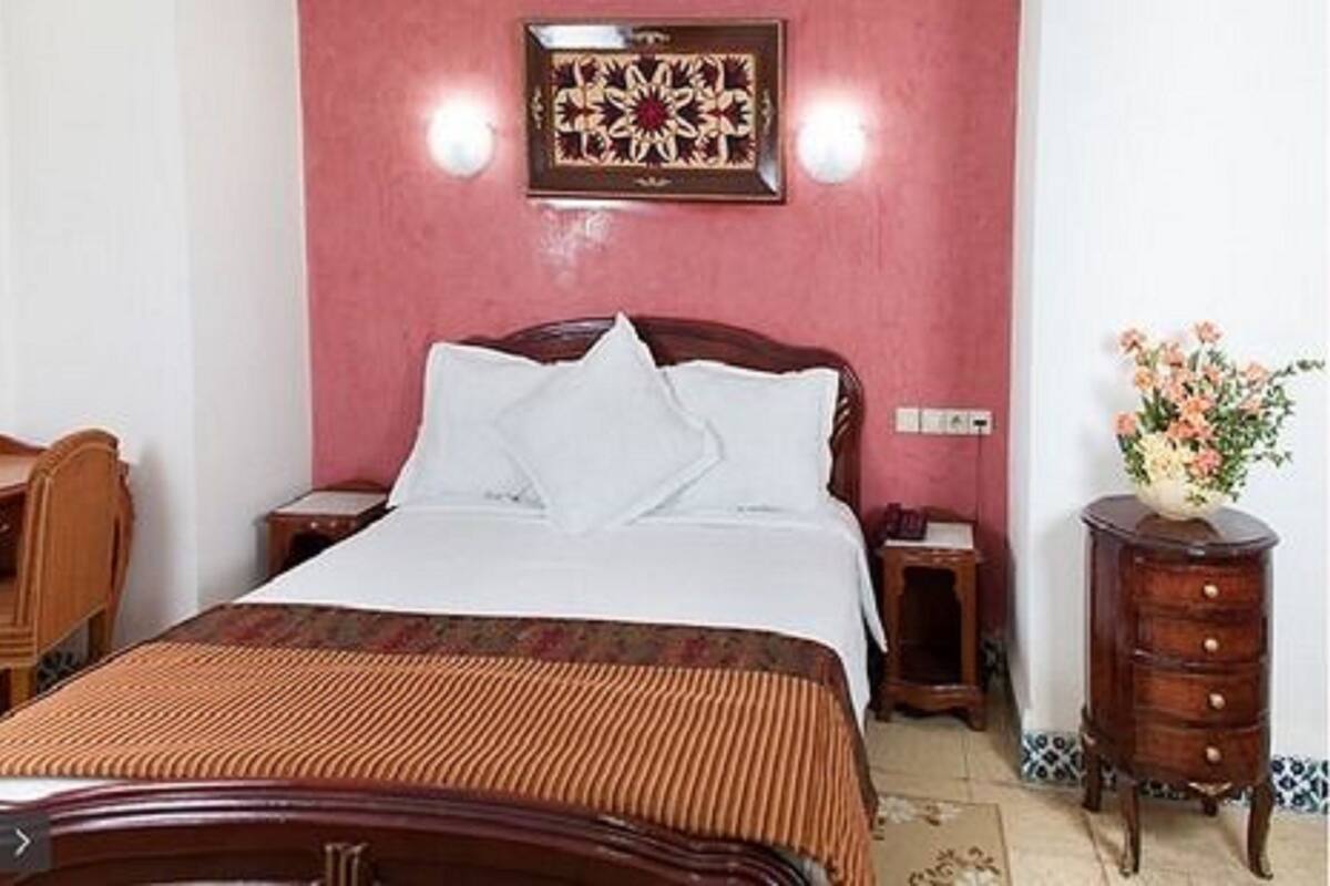 A hotel room with a bed, wooden nightstands, a desk, and a dresser.