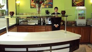 A hotel reception area with a glass counter, wooden cabinets, and a vase with flowers. - Hotel Sweet (Algiers)