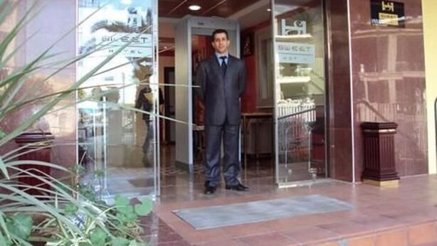 A man in a suit standing at the entrance of a building with a glass door and a sign that reads "SWEET". - Hotel Sweet (Algiers)