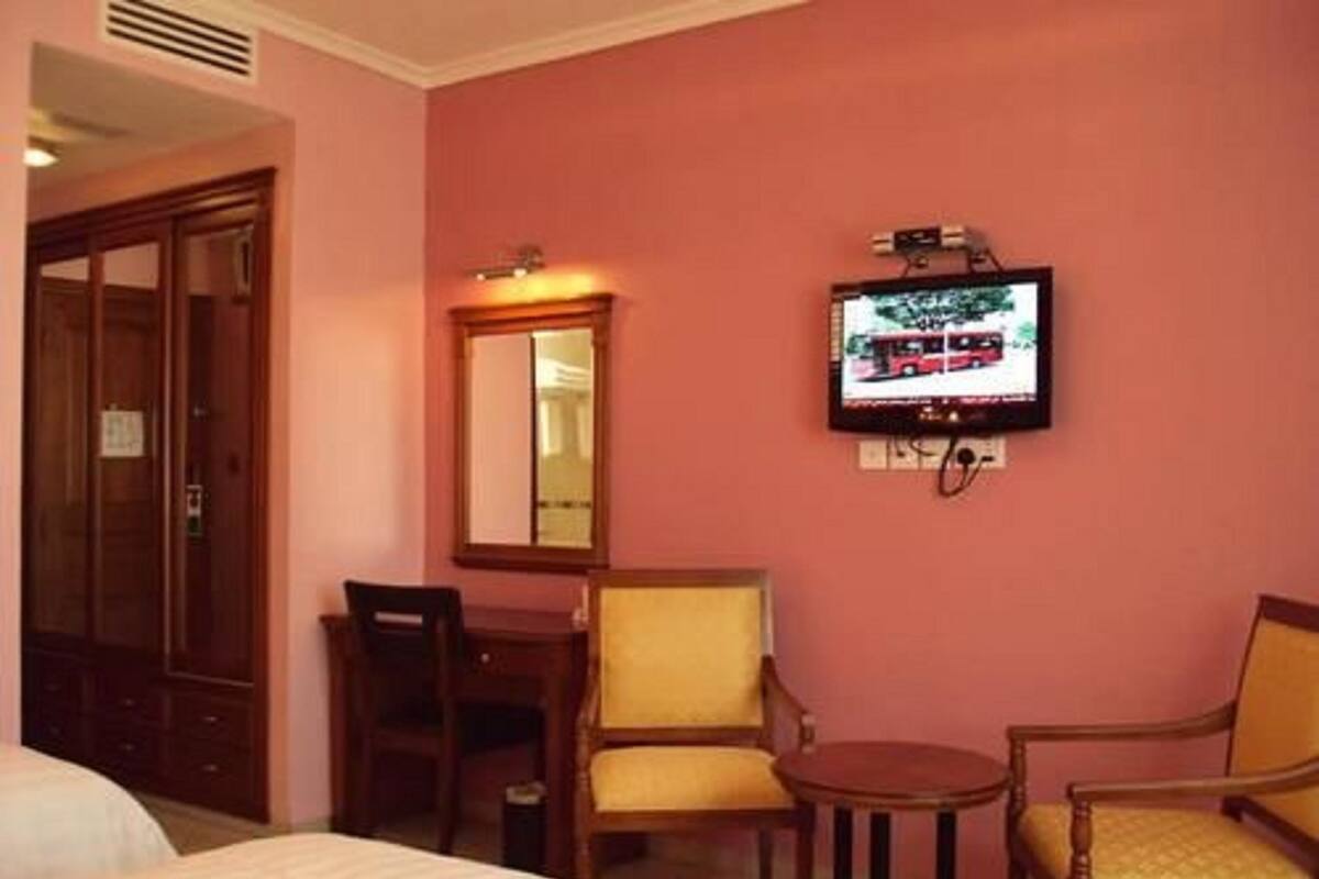 A hotel room with a bed, a desk, two chairs, a television, and a mirror.