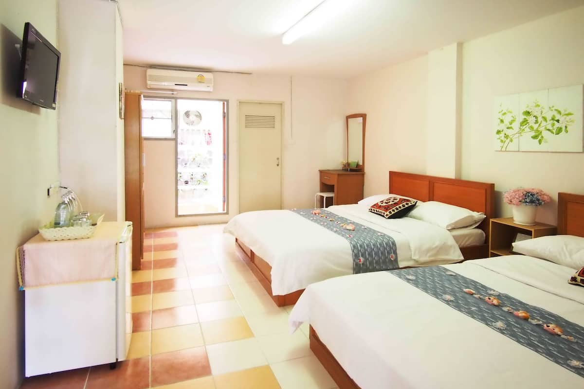 Quarto de hotel com duas camas, televisão, escrivaninha, cadeira, janela e porta.