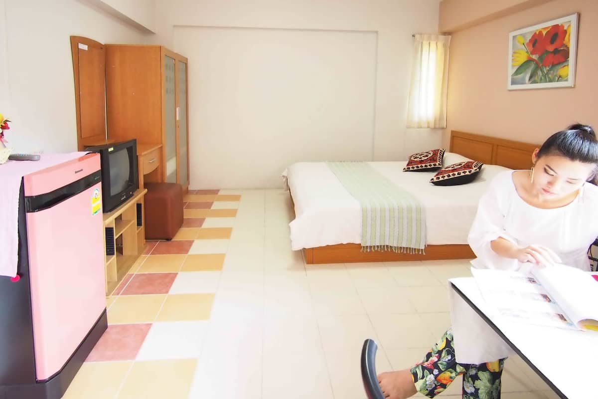 Quarto de hotel com cama, escrivaninha, televisão e frigorífico.