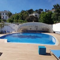 Una piscina al aire libre de temporada, sombrillas