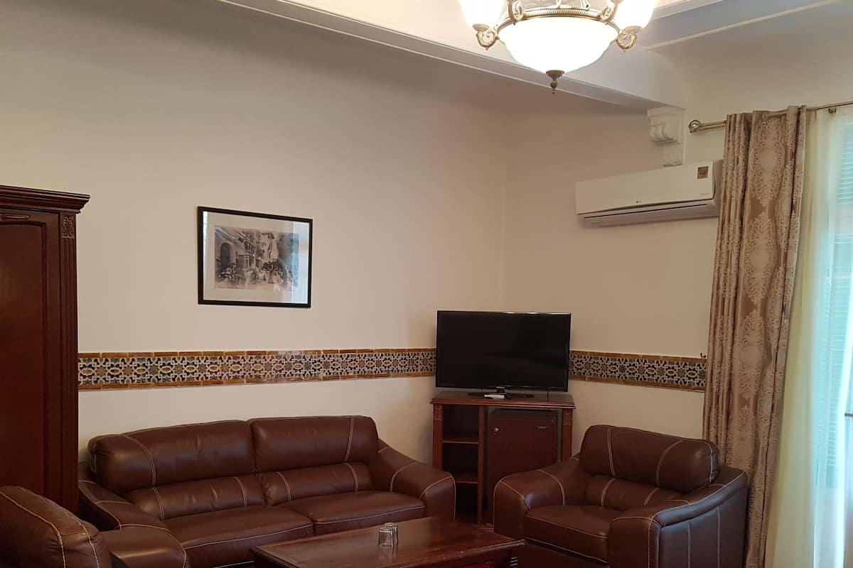 A living room with a brown leather sofa, a matching armchair, a coffee table, and a flat-screen TV on a stand.