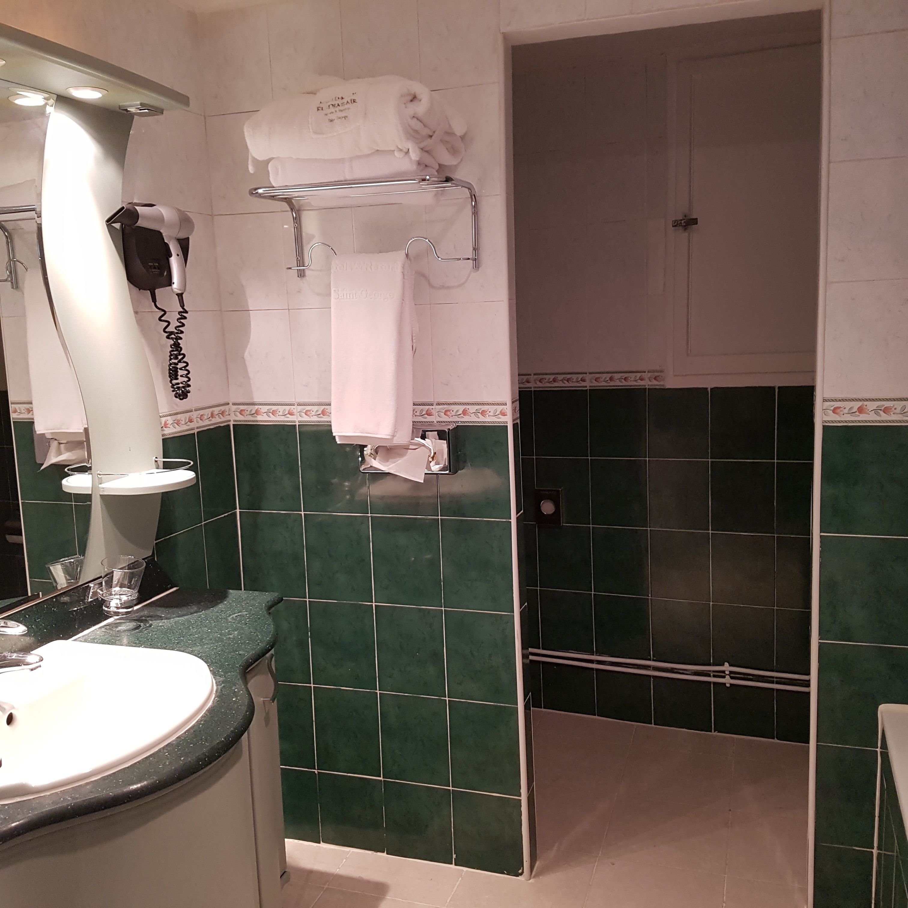 Une salle de bain équipée d’un lavabo, d’un sèche-cheveux et d’un porte-serviettes avec des serviettes.