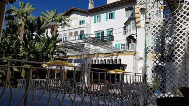 A building with balconies, a covered outdoor seating area, and a lattice fence. - Hotel El-Djazair (Algiers)