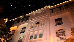 A white building with multiple windows and balconies, illuminated at night. - Hotel El-Djazair (Algiers)