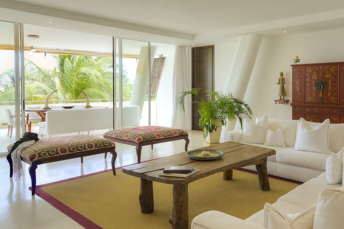 A spacious living room with a white sofa, a wooden coffee table, and a dining area with a white table and chairs.