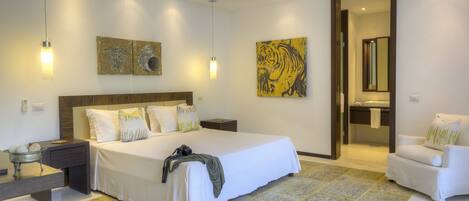 A modern bedroom with a large bed, bedside tables, a chair, and artwork on the walls.