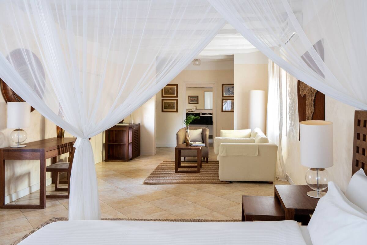 A hotel room with a bed, a sofa, a desk, and a chair.