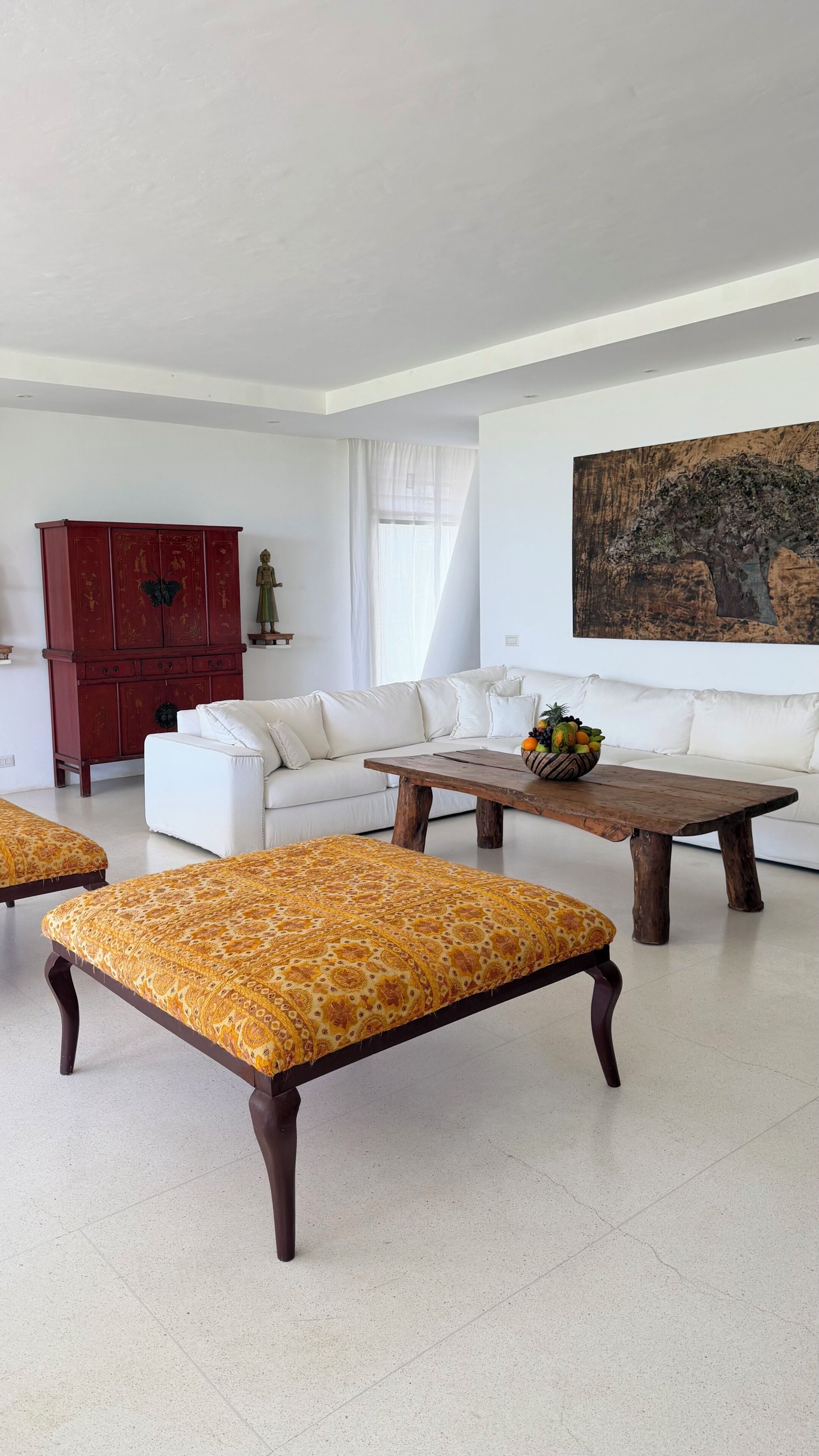 A modern living room with a white sofa, a wooden coffee table, and a red cabinet.