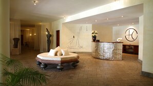 Un vestíbulo con una recepción, un cuadro abstracto grande, una cama y una planta en maceta.