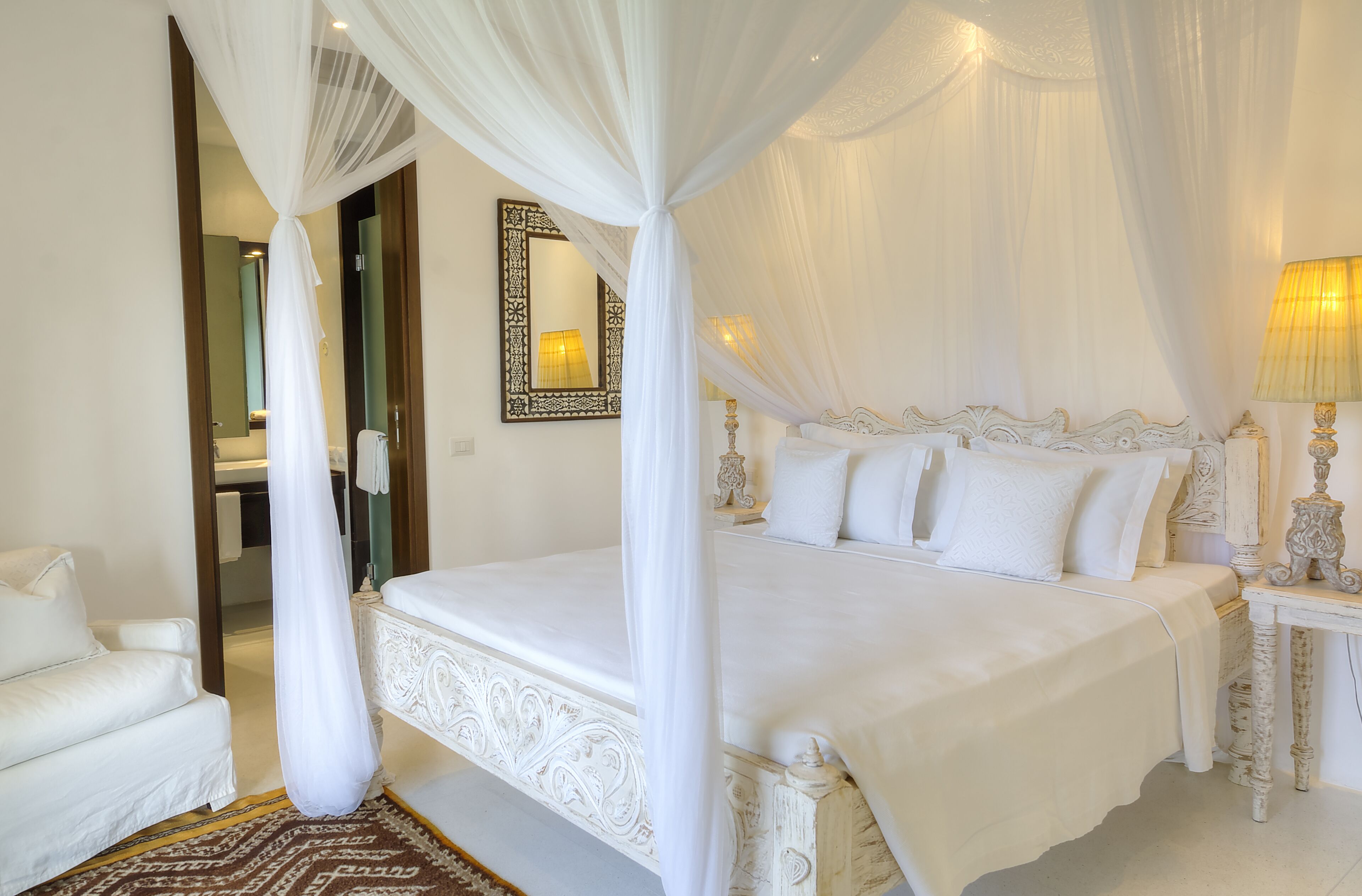 A four-poster canopy bed with white bedding and a matching nightstand.
