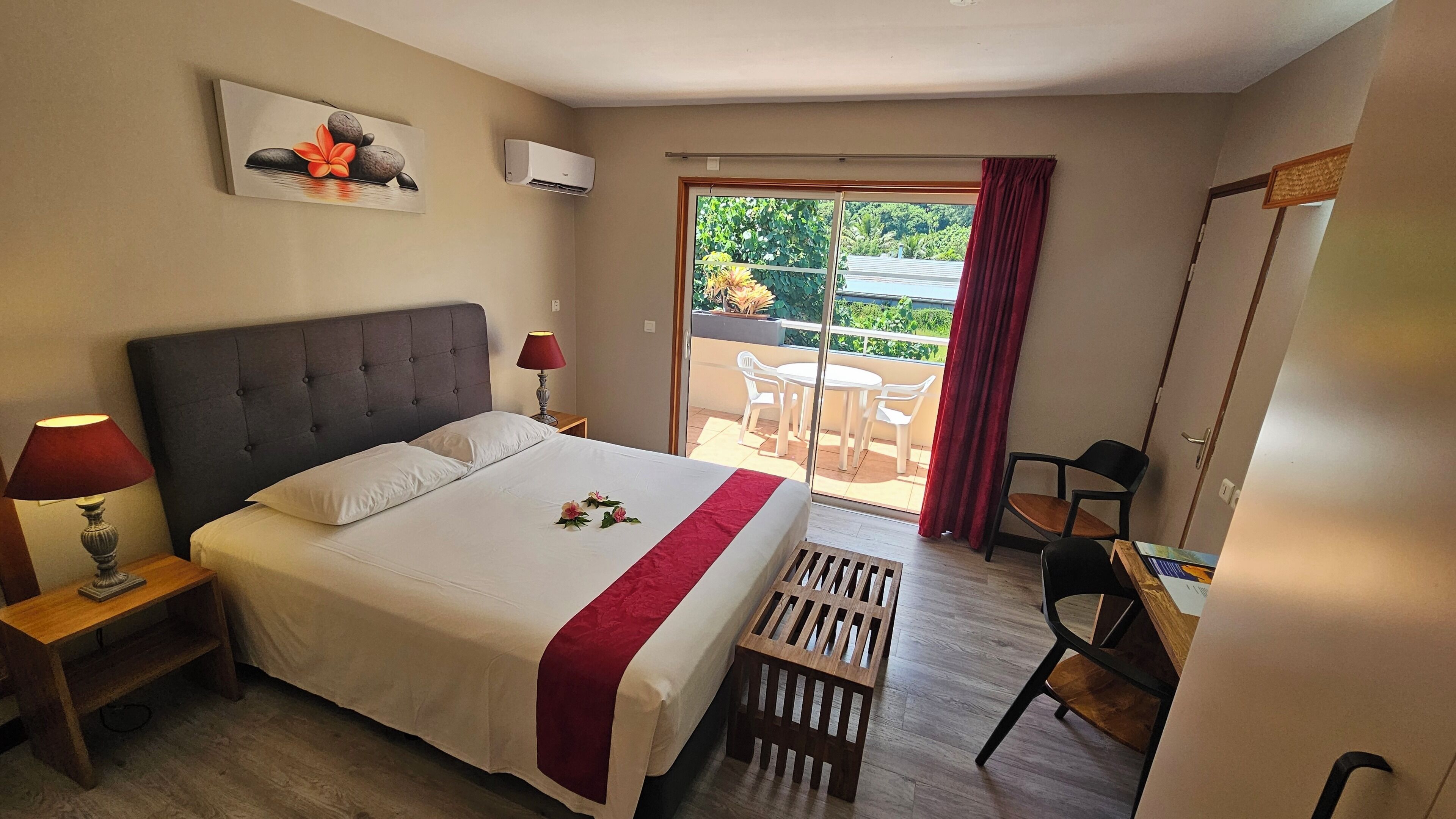 Una habitación de hotel con cama, escritorio, silla, ventana y balcón.
