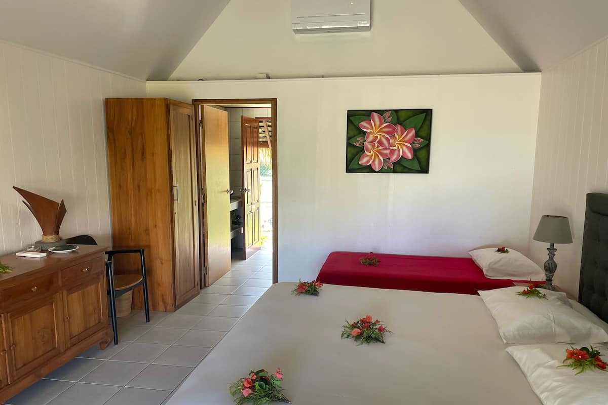 A bedroom with a bed, a desk, a chair, and a painting on the wall.