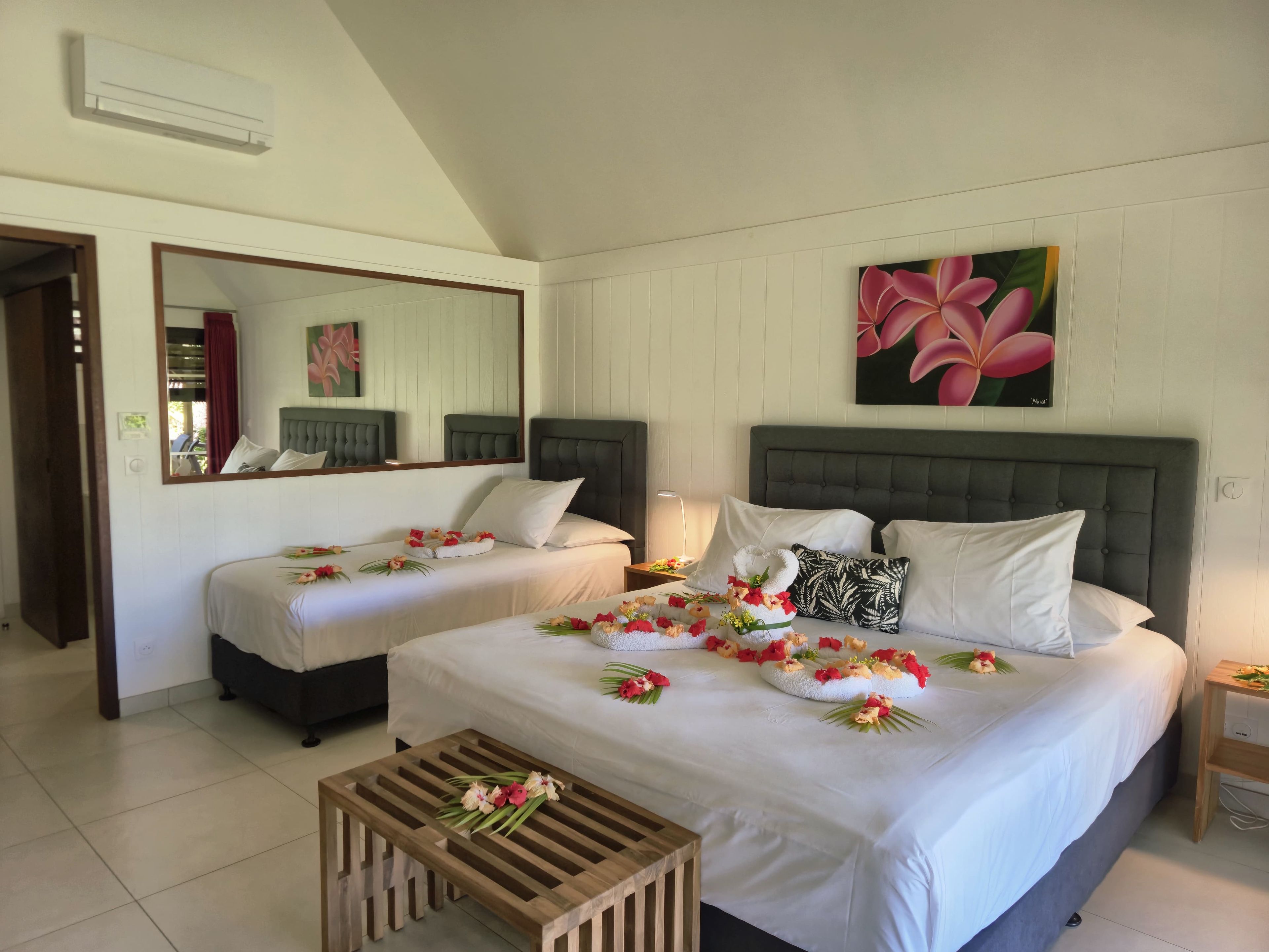 A hotel room with two beds, a wooden coffee table, and a large mirror.