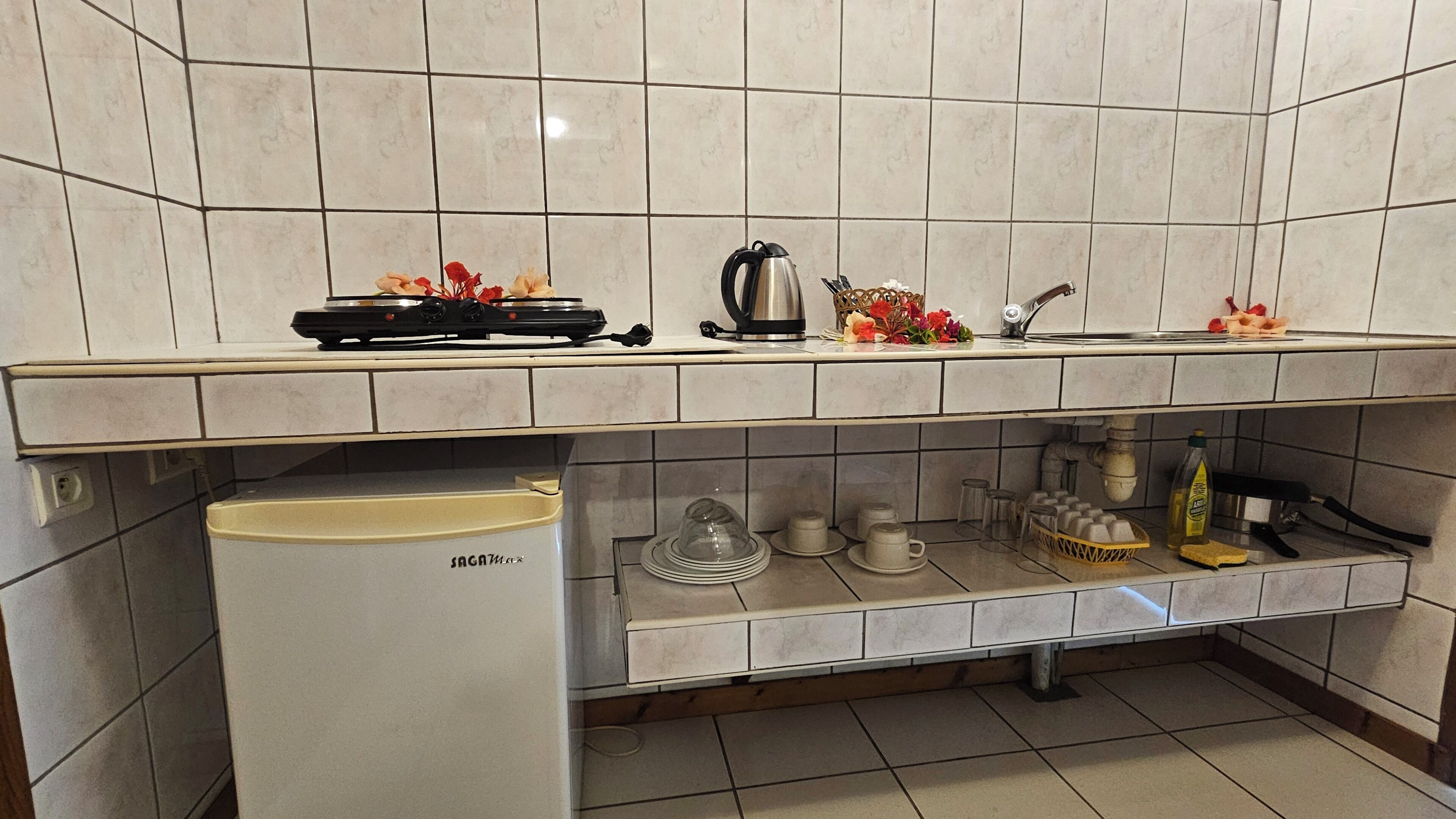 A kitchen with a gas stove, kettle, and various kitchenware.