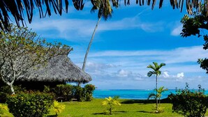 Un complexe hôtelier tropical doté de bungalows aux toits de chaume, de palmiers et offrant une vue sur l’océan.