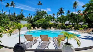 Una piscina al aire libre, sillones reclinables de piscina