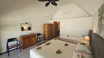 A bedroom with a bed, bedside table, lamp, wardrobe, desk, chair, and a ceiling fan.