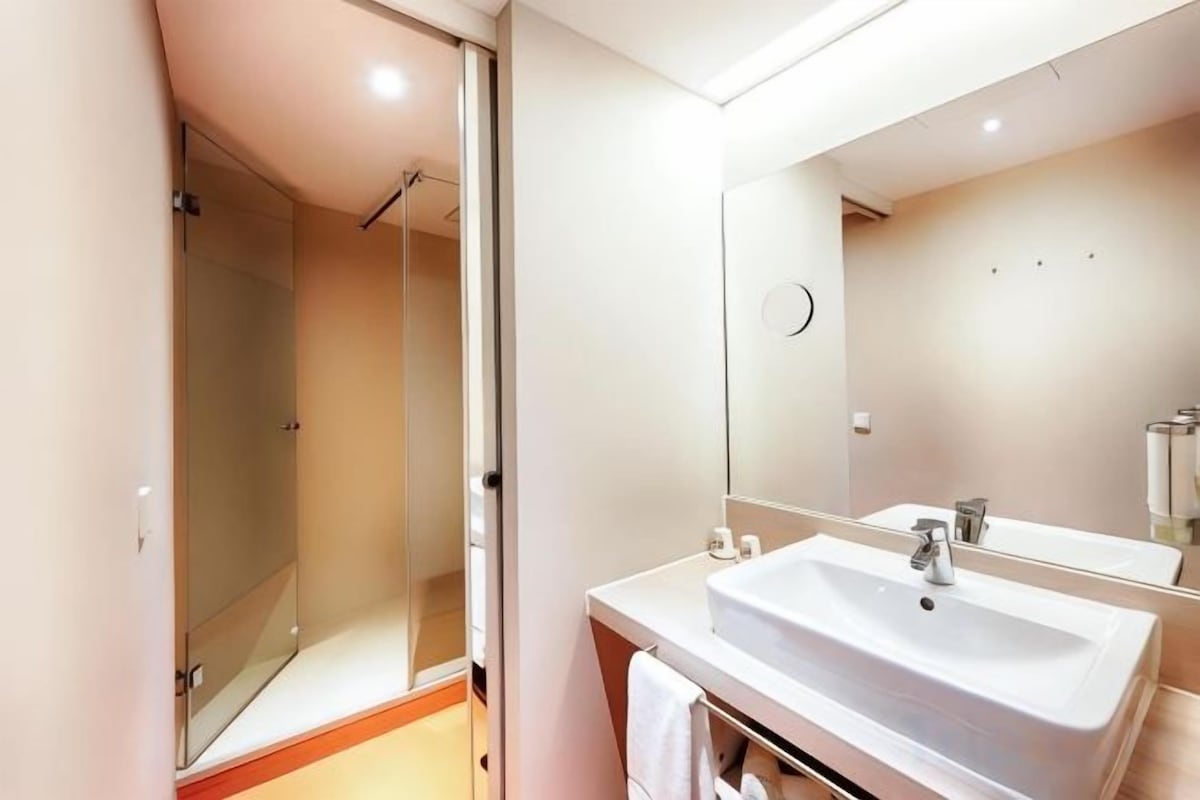 Une salle de bain moderne avec une douche Ă parois de verre, un lavabo avec un miroir et un porte-serviettes.