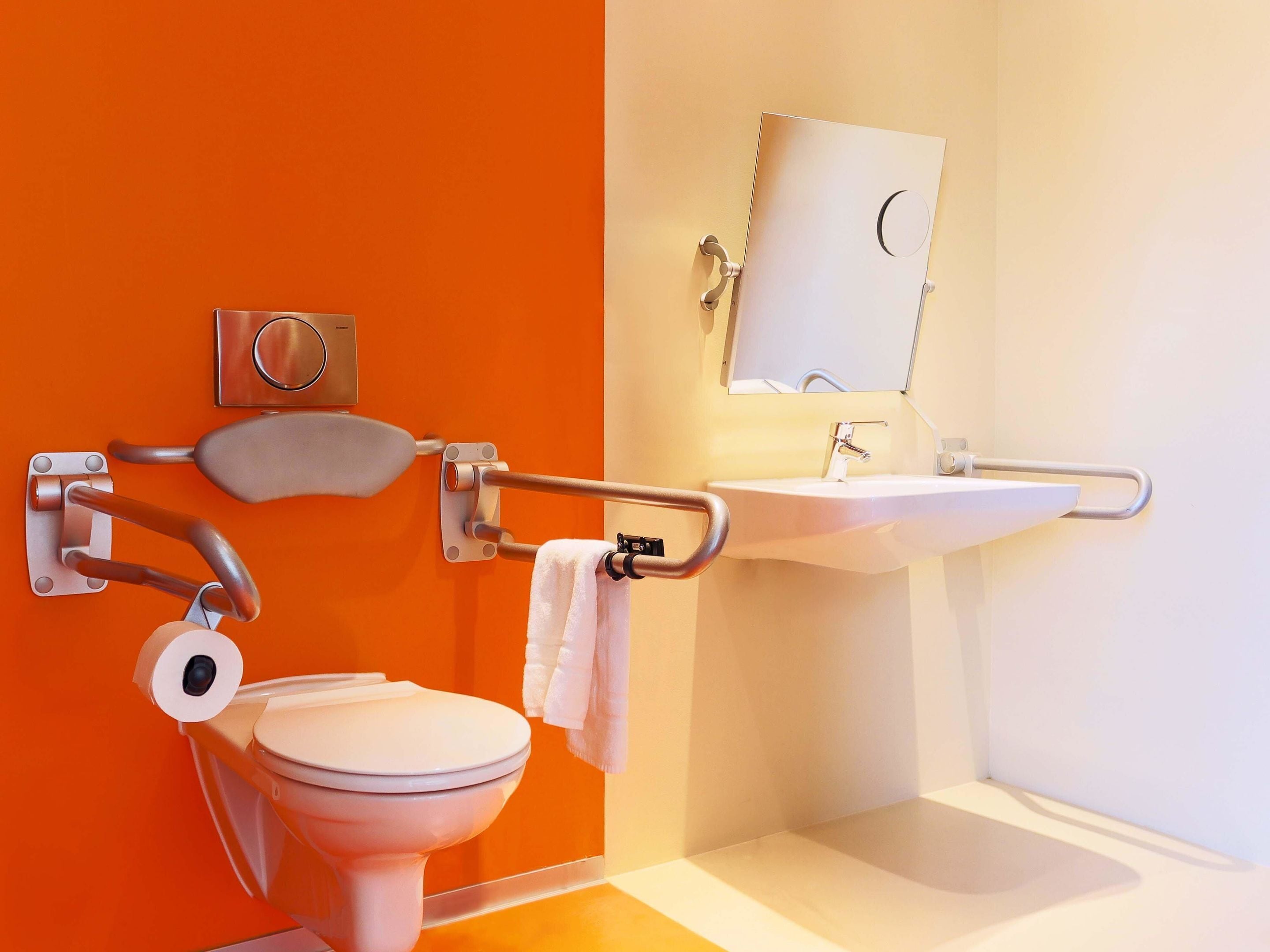 Un baño con inodoro blanco, lavamanos y espejo.