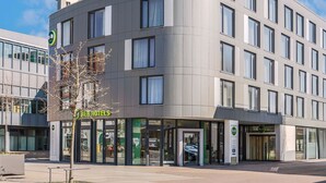 Un hotel moderno con fachada curva, ventanas grandes y una entrada visible con un letrero.